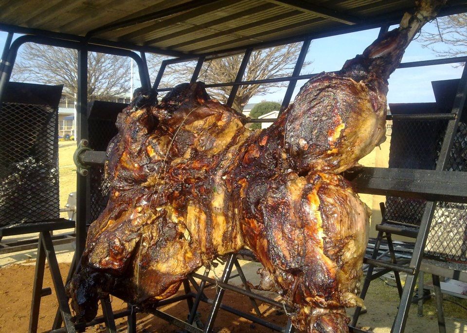 Whole lamb roasting over an open flame on the spit