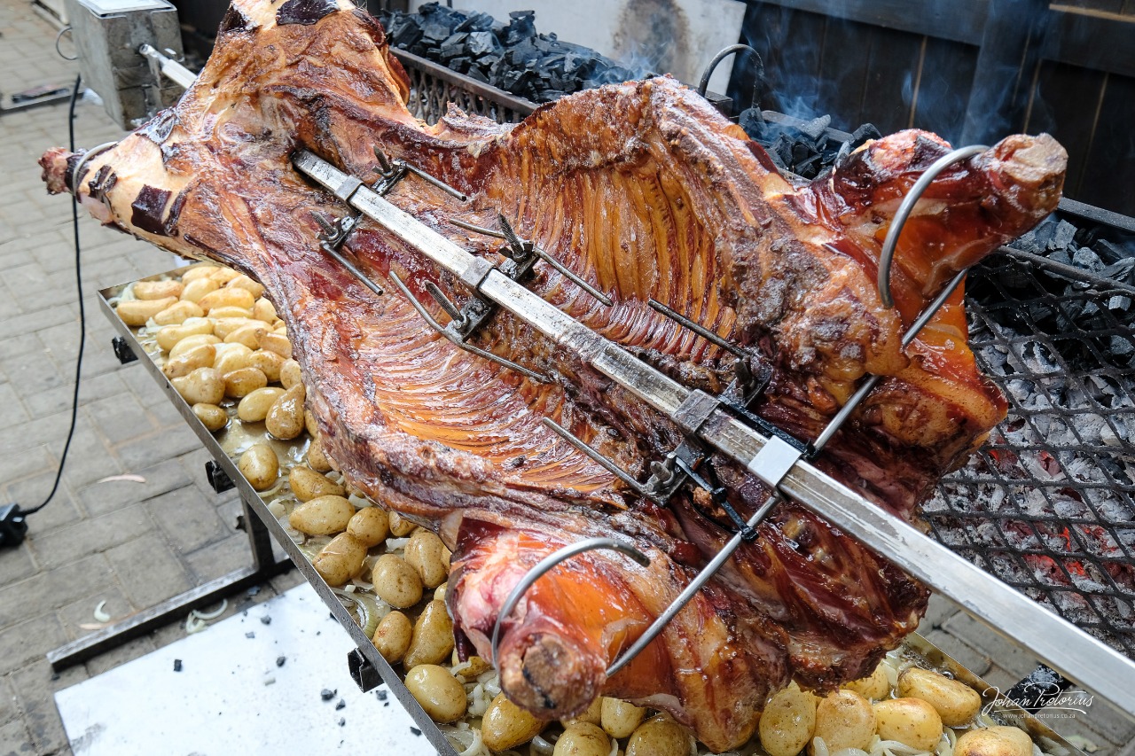 Pork roasting on the spit with potatoes below